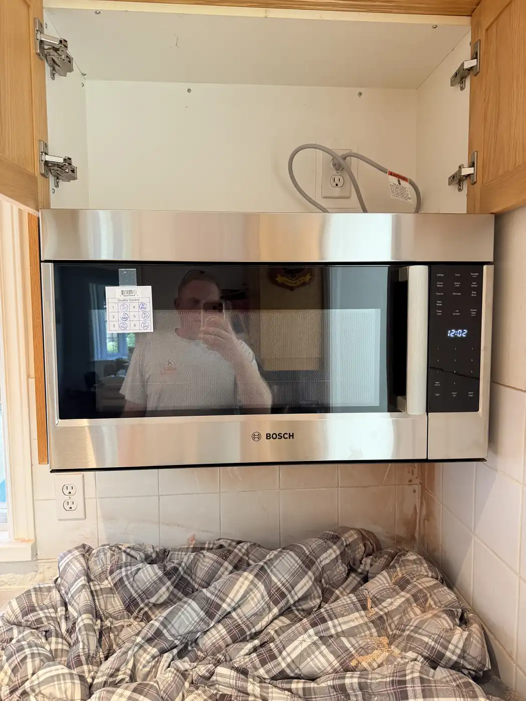 Over-the-range microwave installed with the upper cabinet open showing the outlet and venting in Ottawa