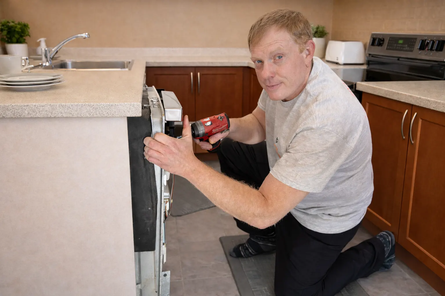 Fixer technician repairing a dishwasher in an Ottawa kitchen