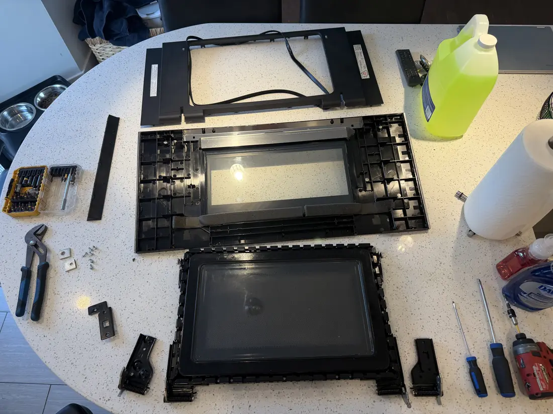 Microwave door disassembled for glass and latch repair in an Ottawa kitchen