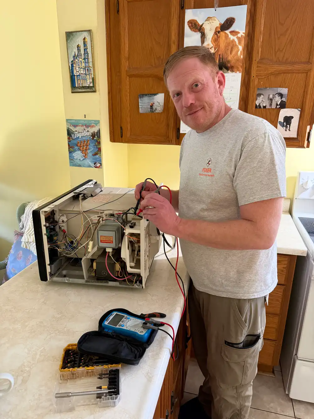 Technician testing an opened microwave's internal components with a multimeter in Ottawa