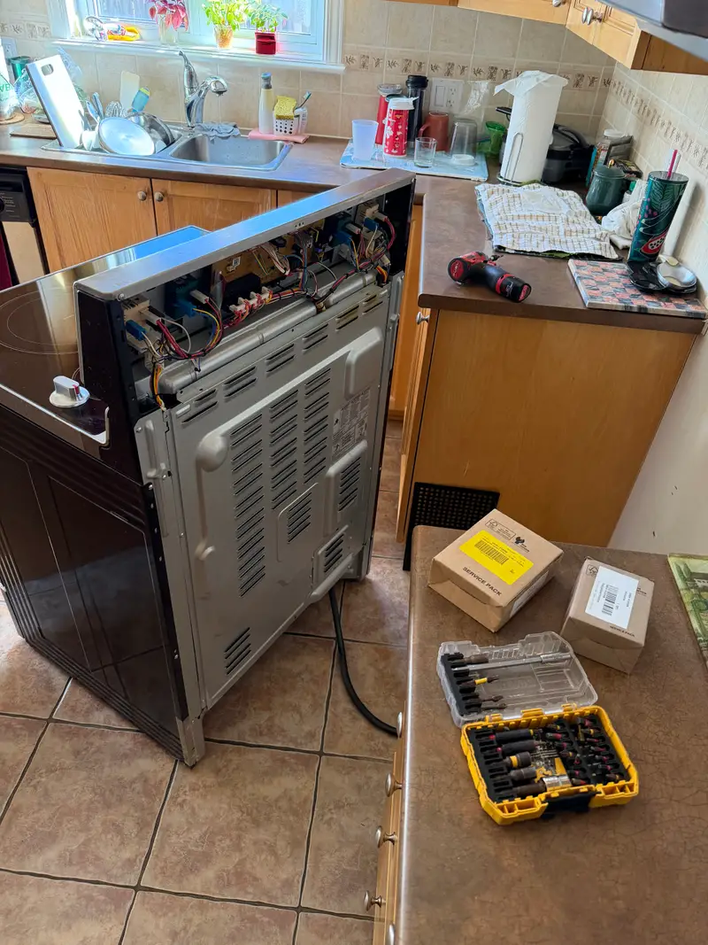 Electric range pulled out showing wiring connections during repair